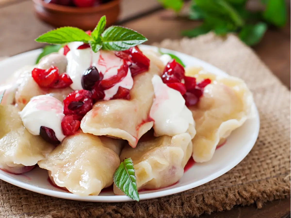 Pierogi dolci polacchi ripieni di frutta fresca di stagione e serviti con panna.