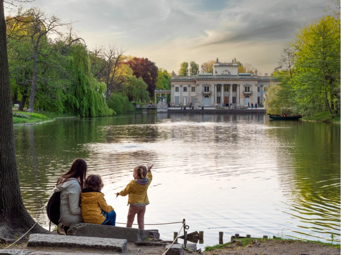 Famiglia con bambini che passeggia nei Giardini Reali di Varsavia con vista sul Palazzo sull’Isola