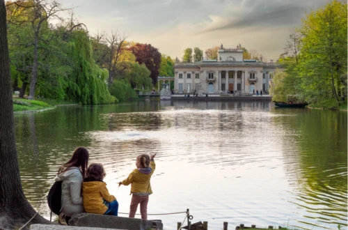 Famiglia con bambini che passeggia nei Giardini Reali di Varsavia con vista sul Palazzo sull’Isola